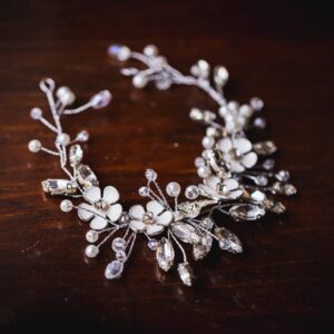 Close-up of a floral crystal necklace on a dark wooden surface.